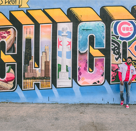 A man posing near graffiti that says Chicago