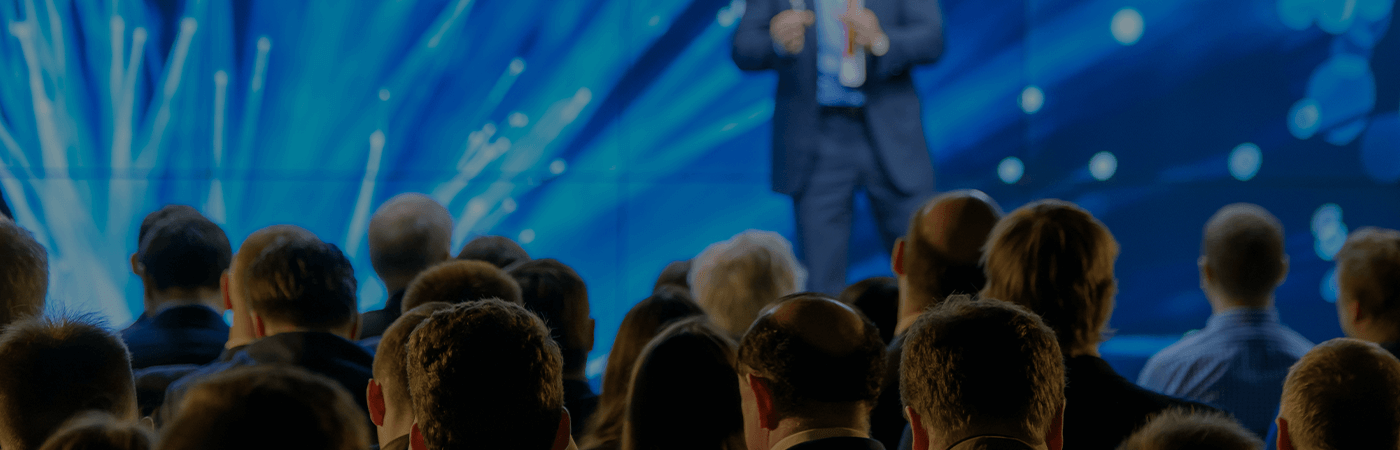 Group of people listing to a person standing on stage