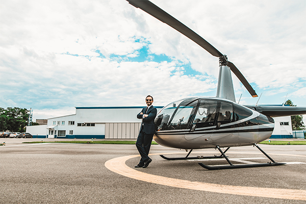 A man wearing a suit standing in front of helicopter