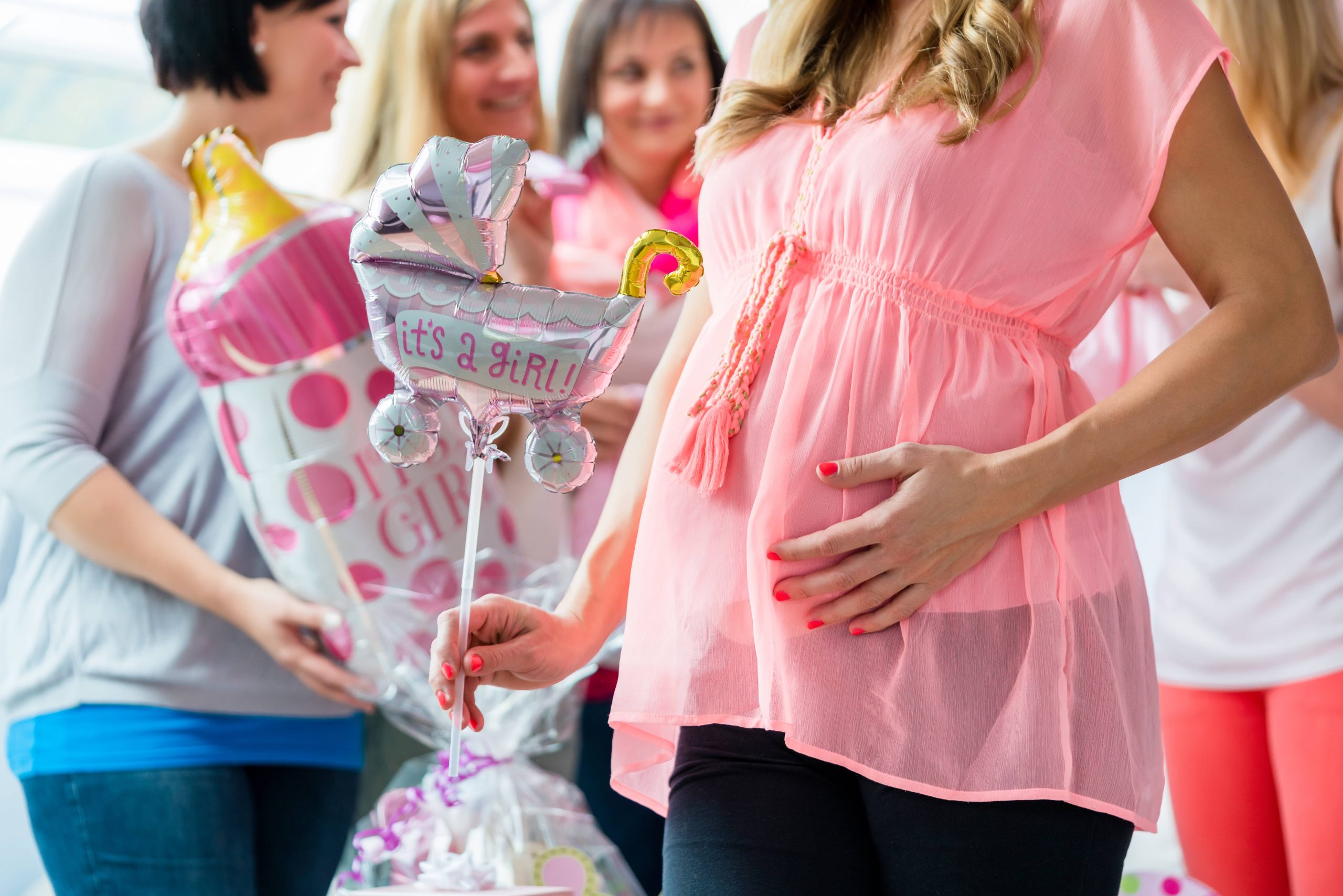 A pregnant woman holding its a girl sign in hand