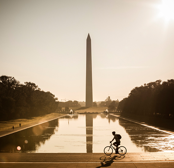 A boy riding a cycle in front of American monuments